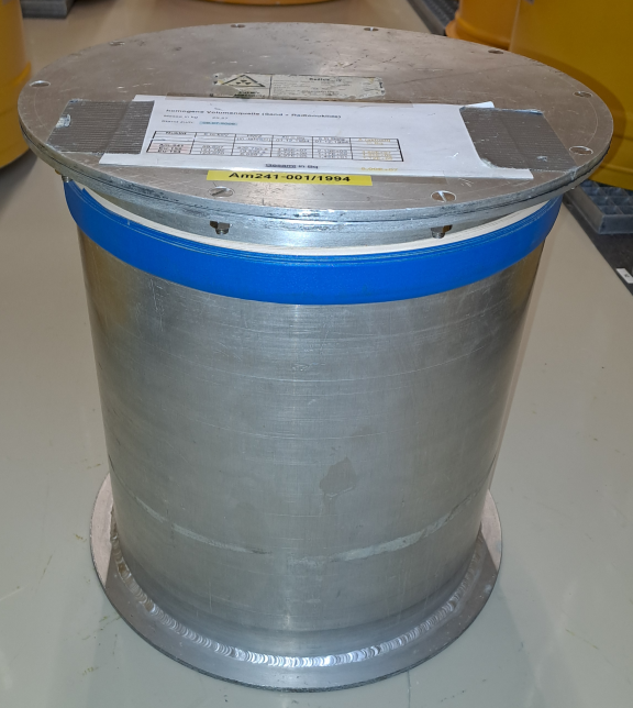 Photo of a volume source (dimensions: height: 36.5 cm, diameter: approx. 35.0 cm; weight: 4733 g; aluminum container; matrix: sand; radionuclides: 152-Eu, 154-Eu, 241-Am).